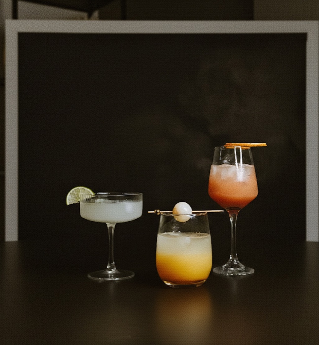 Three Club Citrine signature mocktails — a lime coupe, a lychee-peach pour and a guanábana spritz — styled on a dark bar
