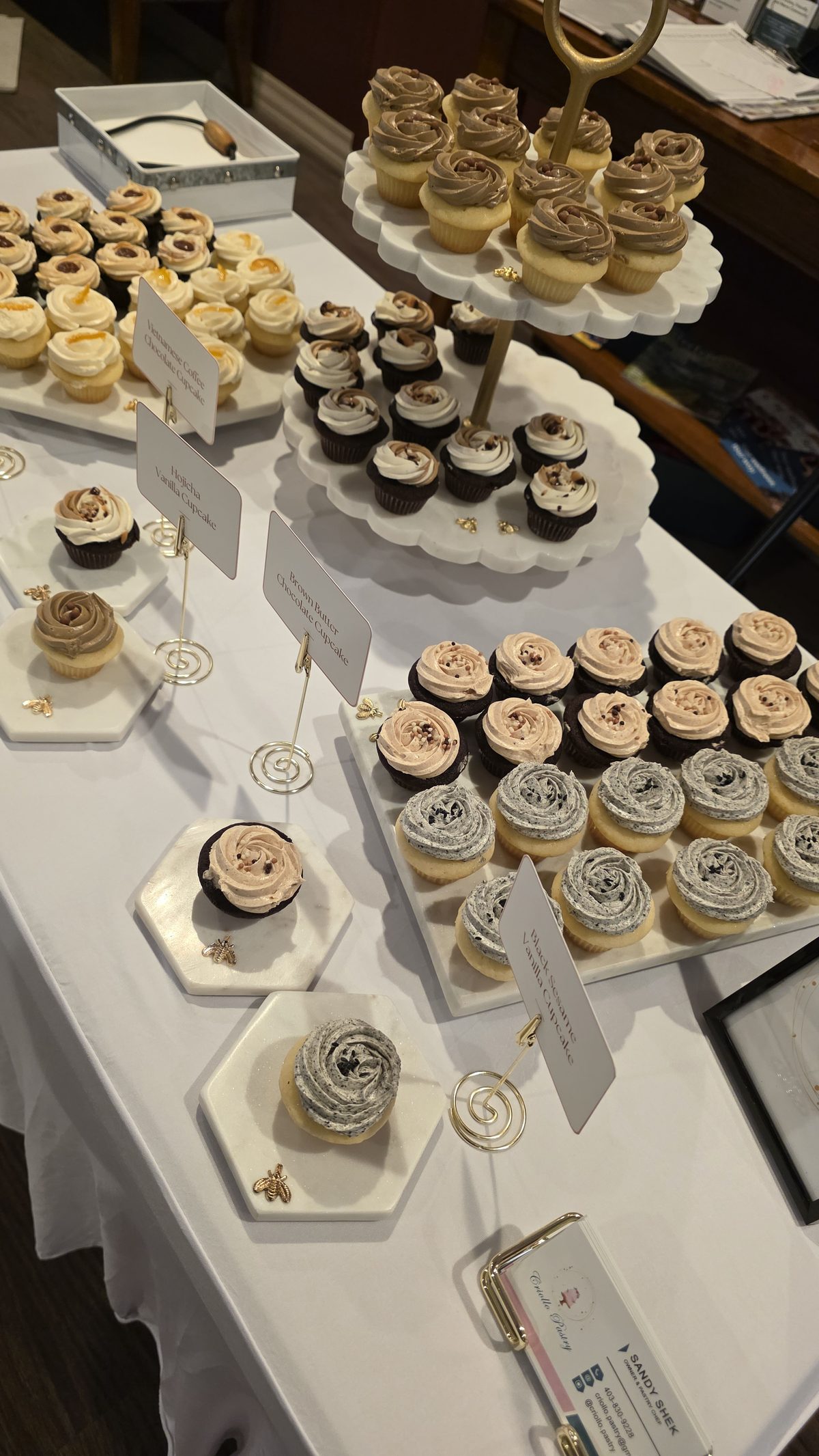A Criollo Pastry table of cupcakes and small bites on tiered stands.
