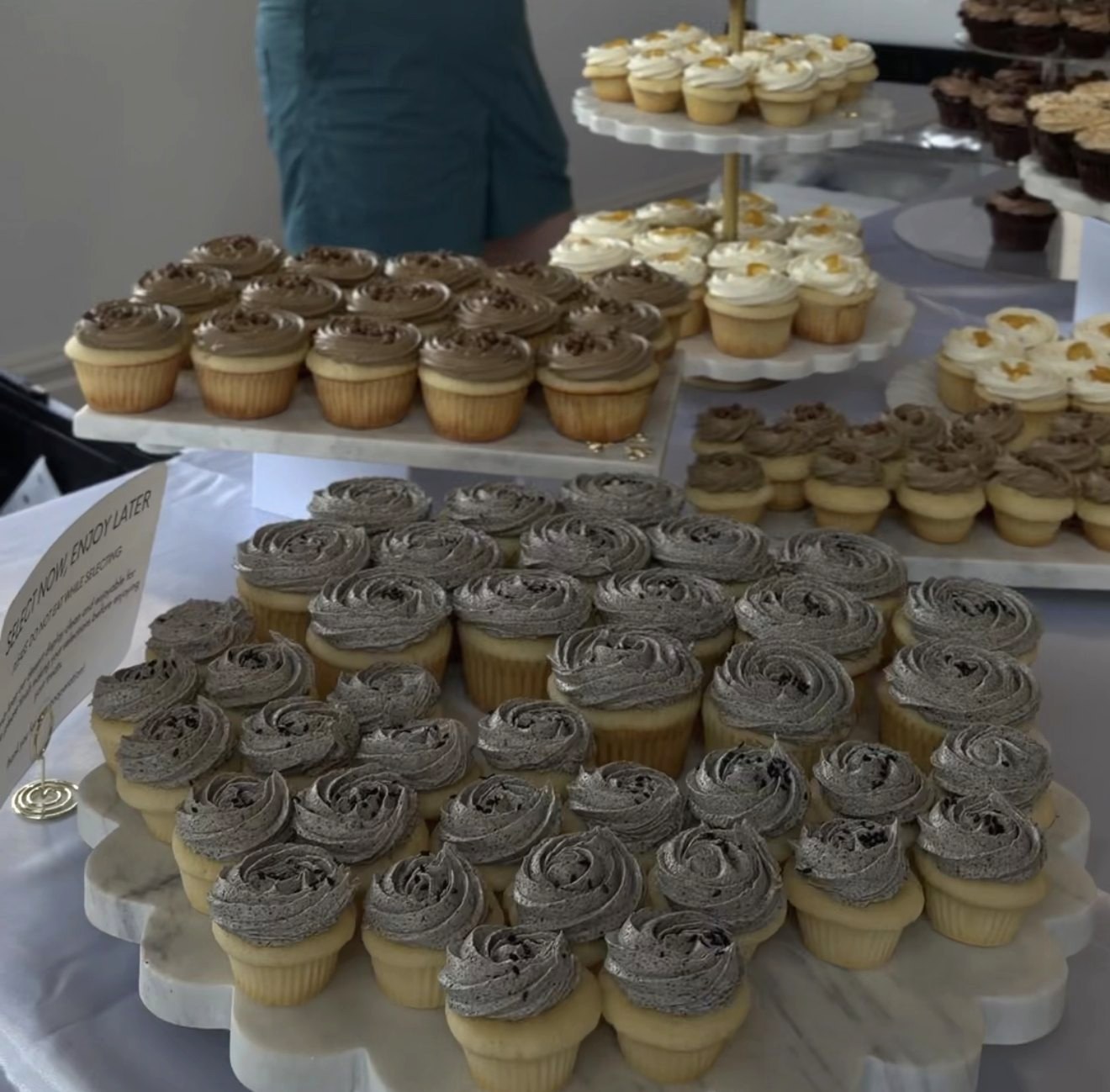 Trays of Criollo Pastry cupcakes on marble stands, finished with swirled buttercream.